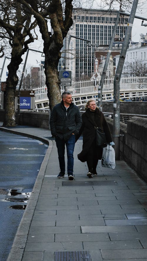 Adult Man and Woman Walking on the Sidewalk 