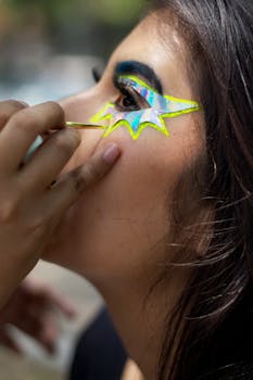 A detailed close-up of a person applying creative and colorful eye makeup.
