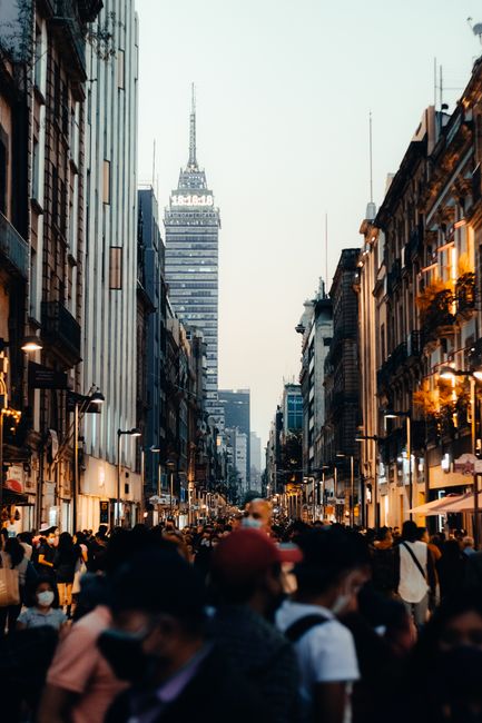 A bustling Mexico City street scene with the iconic Torre Latinoamericana in the background at dusk.