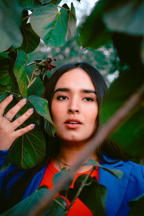 Free A woman in a blue blazer poses among green leaves in Zapopan, Mexico. Stock Photo
