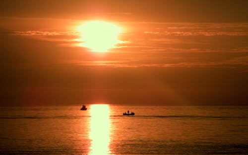 Free Silhouette of Boats Sailing in the Ocean During Golden Hour  Stock Photo