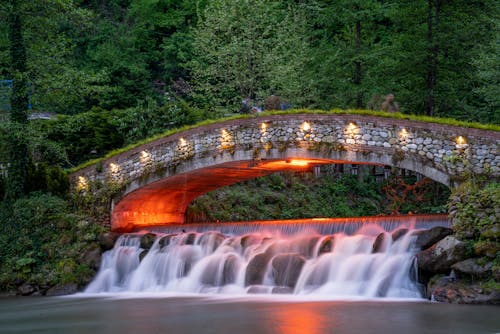 Illuminated Waterfall and Bridge in Park