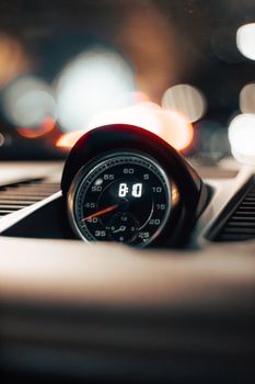 Detailed close-up of a car speedometer illuminated at night with a bokeh effect in the background.