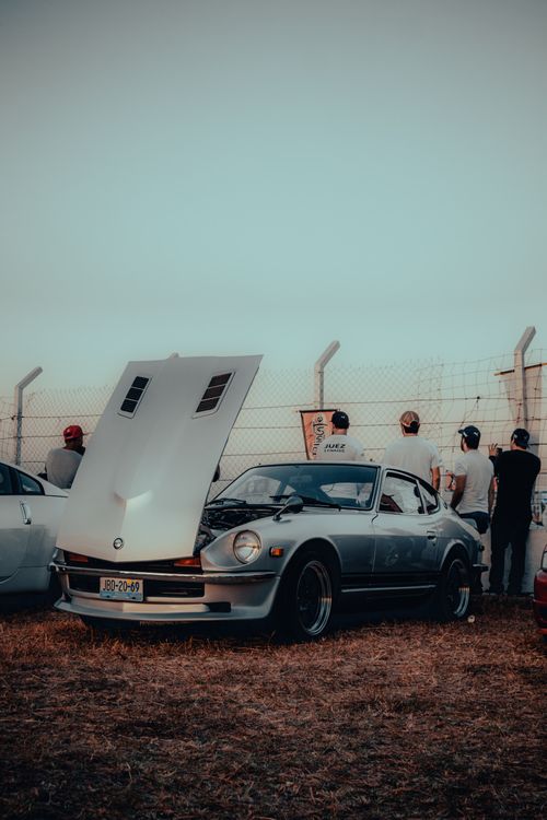 Free Vintage car with hood open parked outdoors in San Pedro Tlaquepaque, Mexico, with people observing in the background. Stock Photo