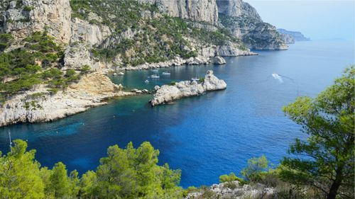 Free Majestic cliffs with blue waters and boats by the sea, perfect for travel enthusiasts. Stock Photo