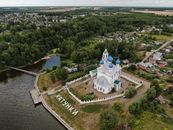 Aerial view of a historic Orthodox church near a river and lush greenery in Russia.