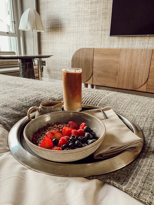 Free Healthy Breakfast with Berries in a Bowl and a Glass with Coffee Standing on a Tray Served to Bed  Stock Photo