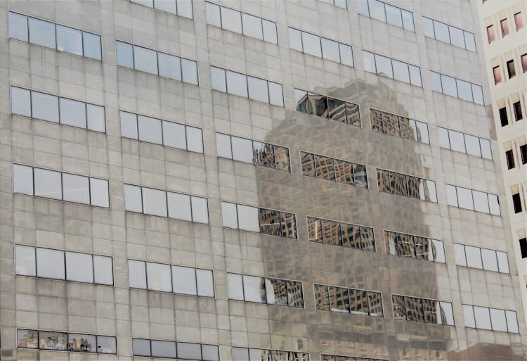 Distorted Reflection Of A Skyscraper In The Glassy Facade Of An Office Building