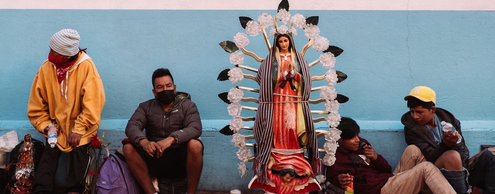 People sitting by a statue of Our Lady of Guadalupe in Ciudad de México, showcasing cultural and religious themes.