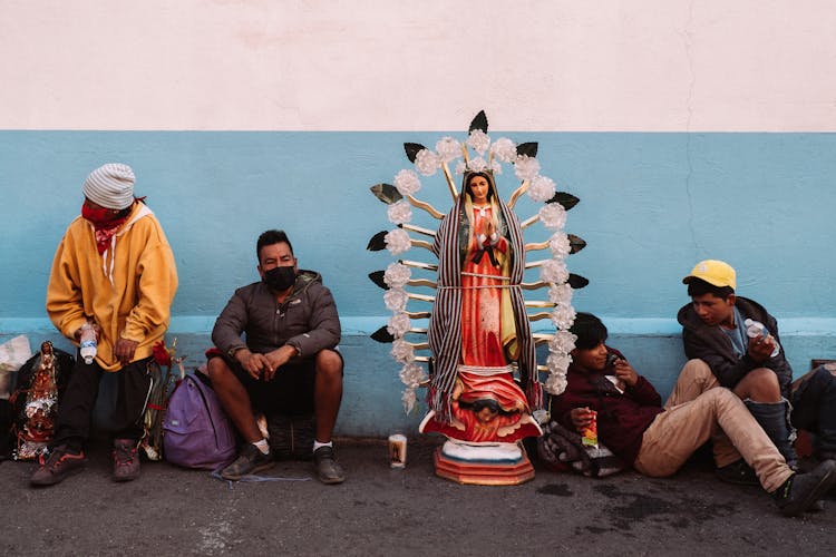 Men Sitting Beside A Religious Statue