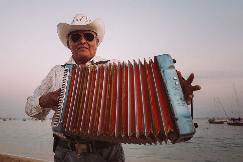 A senior musician with an accordion enjoys music by the sea in Cabo San Lucas.