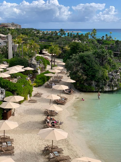 Free Tranquil tropical beach resort featuring palm trees, beach umbrellas, and turquoise waters. Stock Photo