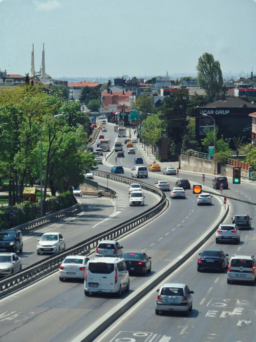 Free An aerial view of a busy city highway with moving cars surrounded by green trees. Stock Photo