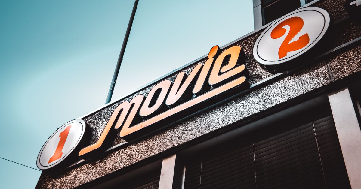 Low-angle shot of a vintage movie theater sign in Bern, Switzerland with a clear blue sky.