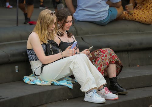 Women Sitting on the Street while Using Their Mobile Phone