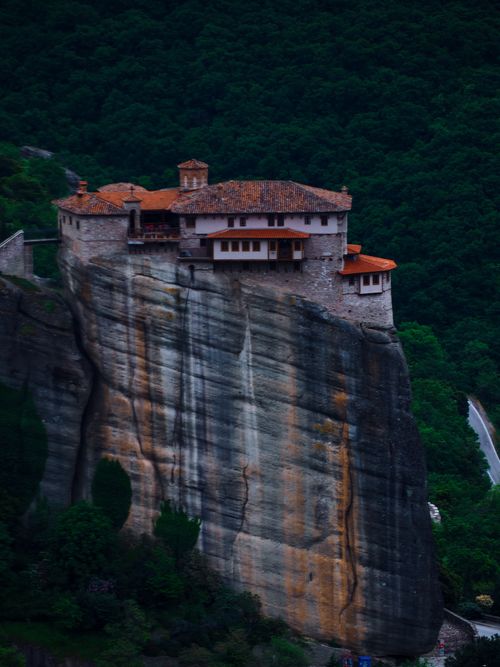 Free A breathtaking view of the Meteora monastery perched atop a towering cliff in Greece, surrounded by lush greenery. Stock Photo