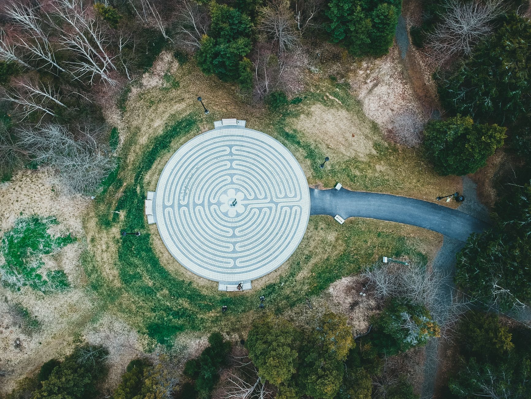 Drone shot of a circular labyrinth in a forest clearing, symbolizing tranquility and reflection.