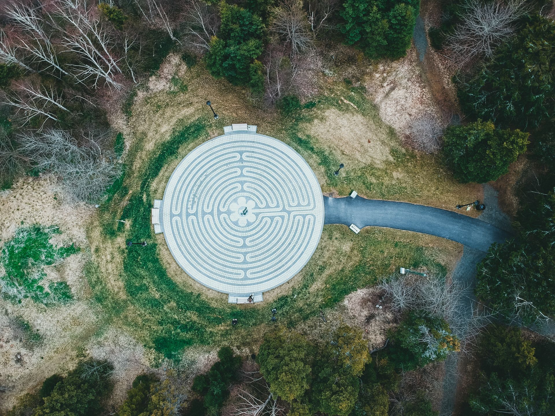 Drone shot of a circular labyrinth in a forest clearing, symbolizing tranquility and reflection.