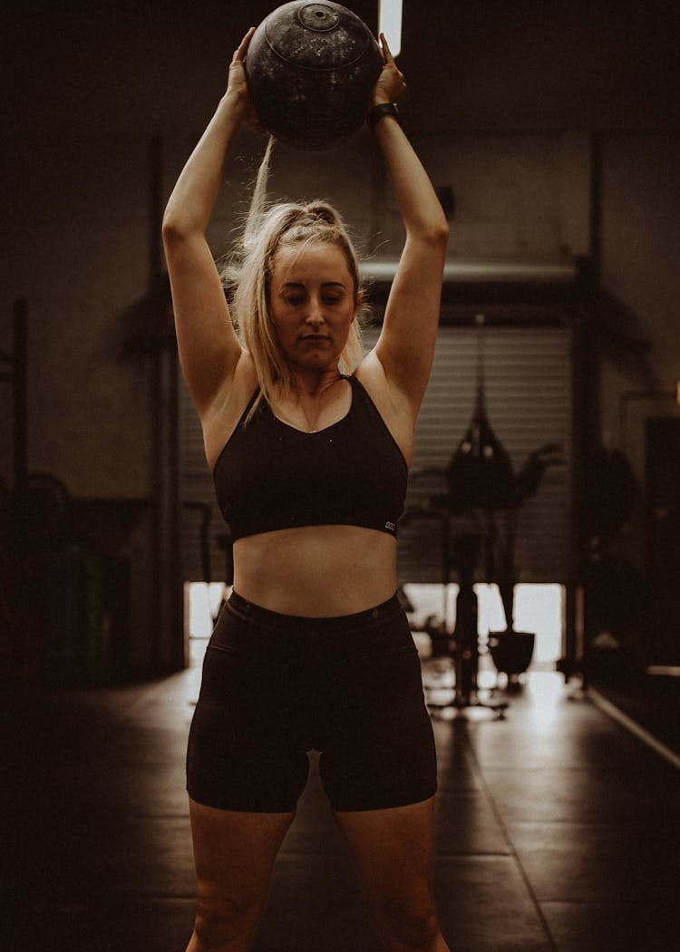 Woman In Fitness Wear Lifting Medicine Ball