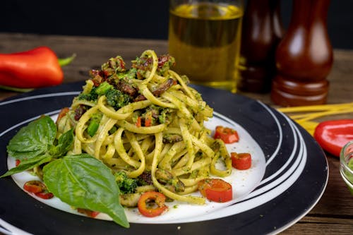 Free Pasta With Green Vegetable on White and Black Ceramic Plate Stock Photo