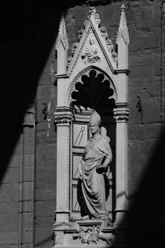 Black and white photo of a Gothic statue on a historic Florence building facade.