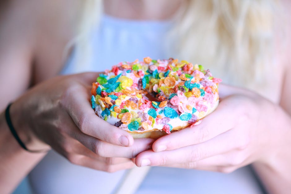 Person Holding Doughnut With Toppings