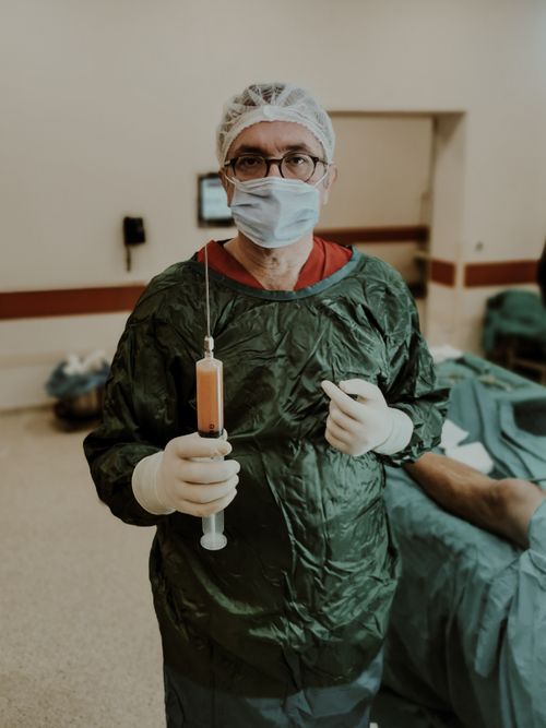 Free A medical doctor in an operating room holds a large syringe, preparing for surgery. Stock Photo