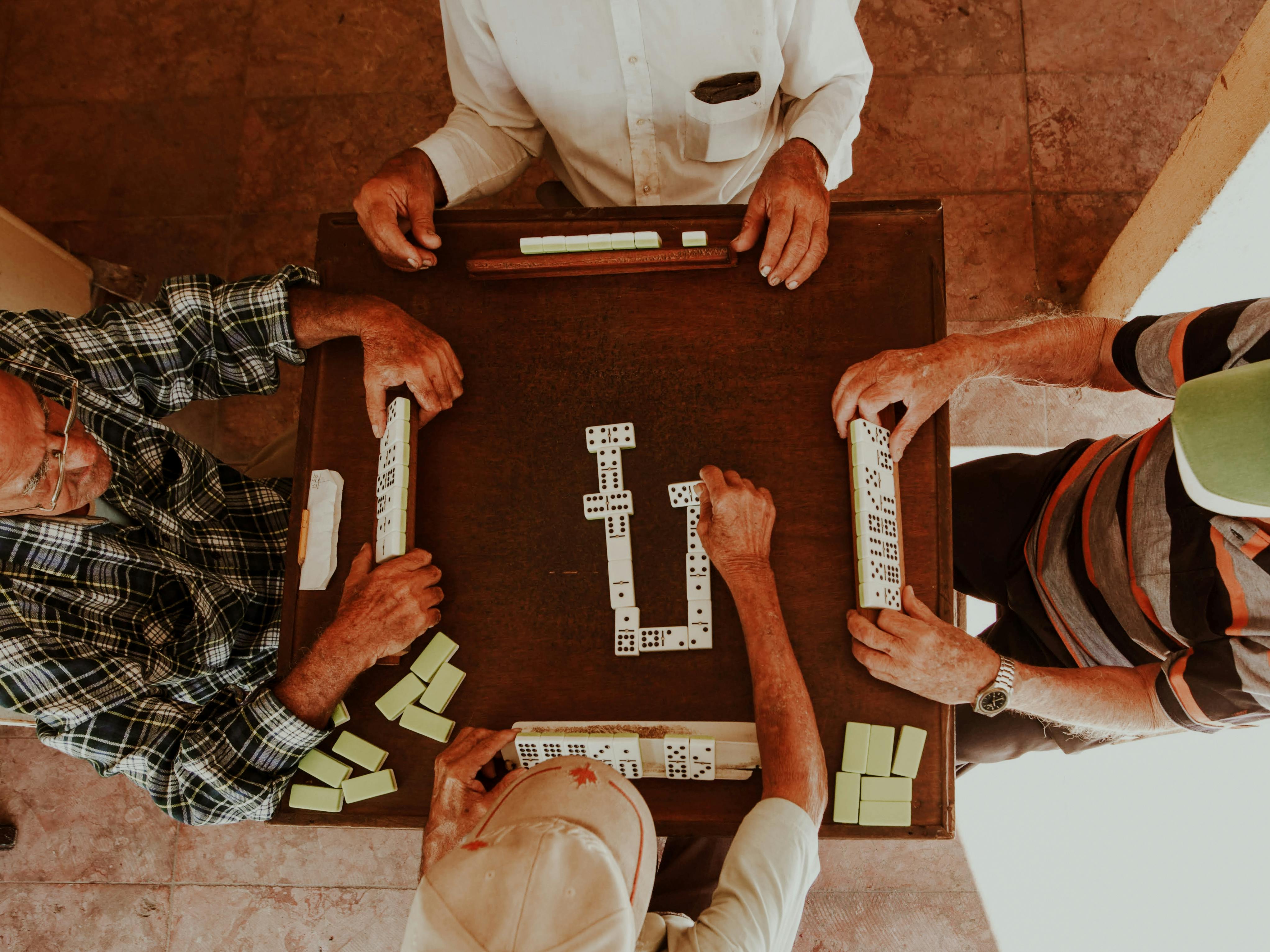 Senior adults playing dominoes indoors, capturing the fun and companionship of game time together.