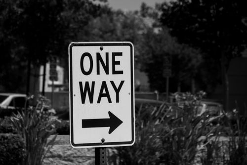 Free Black and white photograph of a one-way street sign with an arrow. Stock Photo