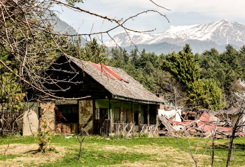 Abandoned Building in a Mountain Valley and View of Snowcapped Mountains in Distance 