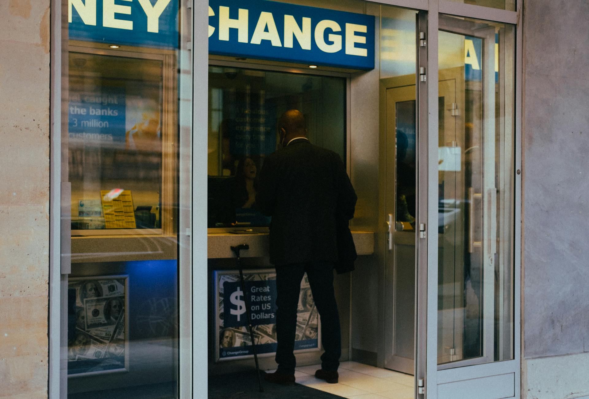 A businessman changes money at a currency exchange counter indoors.