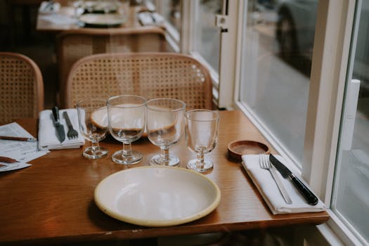 Inviting table setting with glasses and cutlery in a cozy restaurant, showcasing warmth and hospitality.