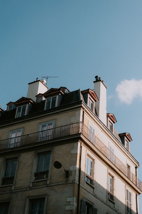Free Low angle view of a classic European apartment building with balconies and a clear blue sky background. Stock Photo