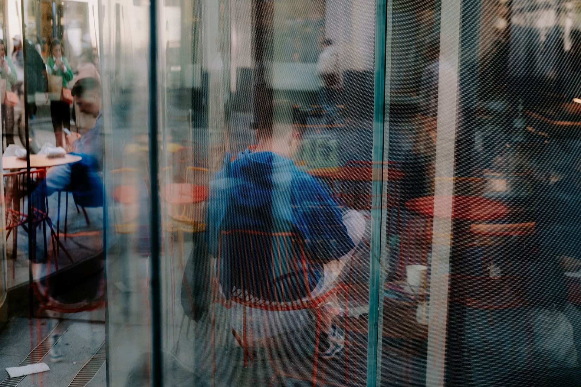 Artistic reflection of people in a café through glass adds a modern urban touch.