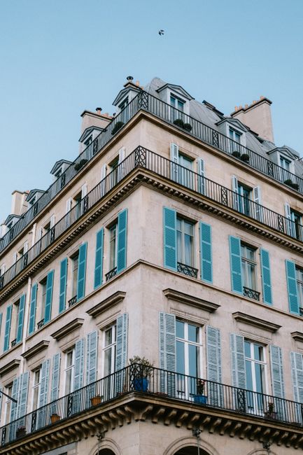 Corner view of a classic urban building with blue shutters, highlighting elegant architecture.