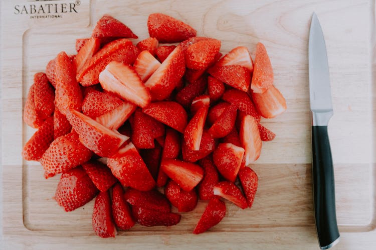 Photo Of Chopped Strawberries And A Knife Lying On Wooden Cutting Board