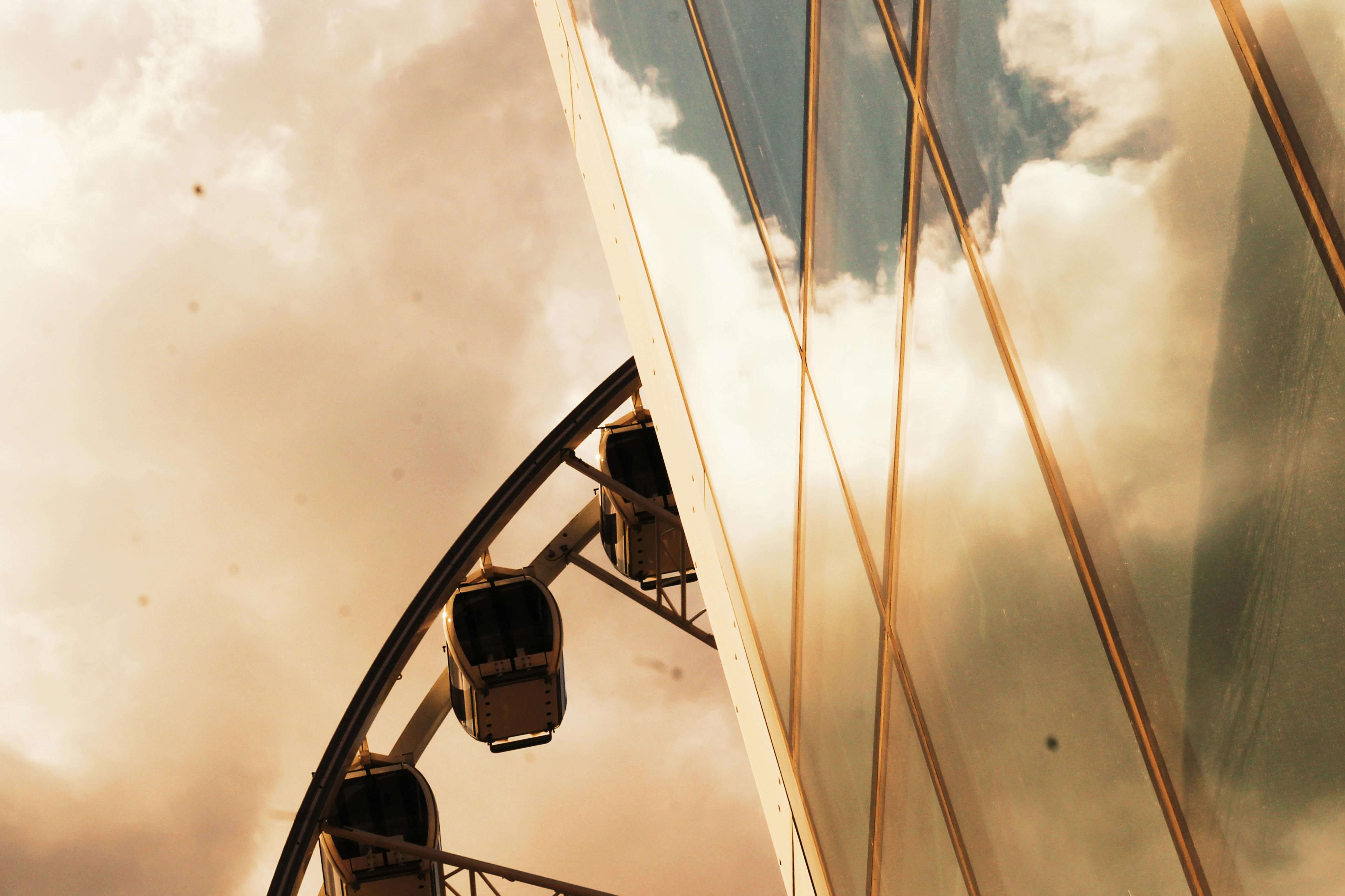 摩天轮在多云的天空下，映照在现代玻璃建筑中