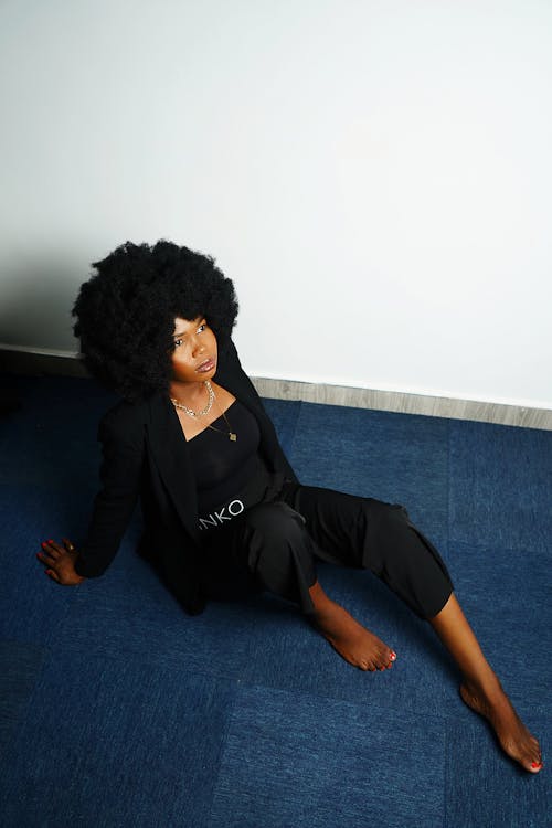 바닥에 앉아 있는 검은색 긴 소매의 여성