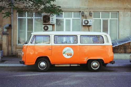 Free Retro orange van parked on an urban street with vintage flair, reflecting nostalgia. Stock Photo