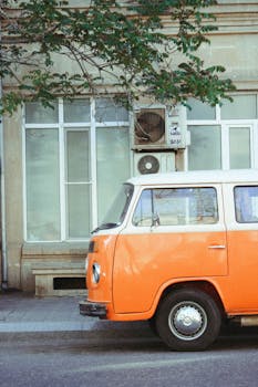 A retro orange van parked on a city street, offering a classic vintage vibe.