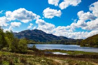 一个宁静的湖泊，风景如画，周围环绕着山脉和郁郁葱葱的绿色植物，在充满活力的蓝天下