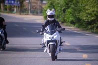 A Man in White Motorcycle Helmet Riding a Motorcycle on Road