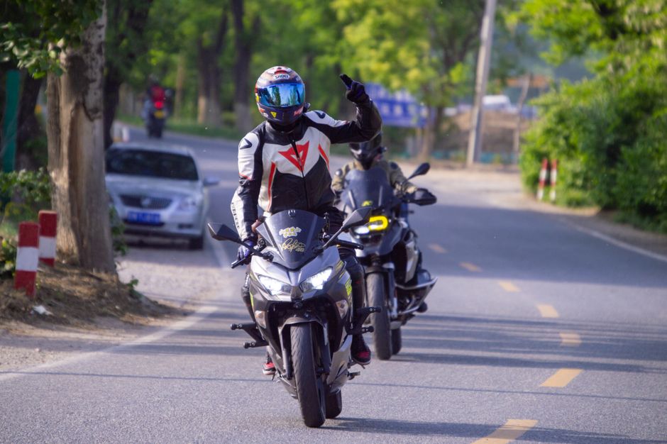 Two motorcyclists enjoy a scenic ride on a tree-lined road, showcasing biking adventure.