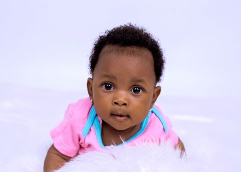 Cute African American baby girl in pink outfit, studio shoot.