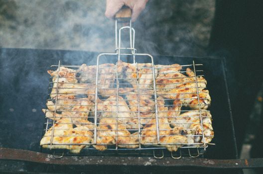 Juicy chicken wings sizzling on a grill, releasing flavorful smoke outdoors.