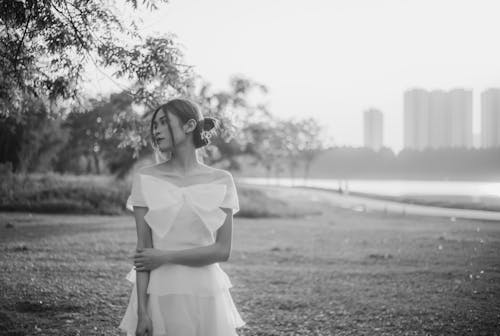 Free Grayscale Photo of Woman in White Dress Standing on Grass Field Stock Photo