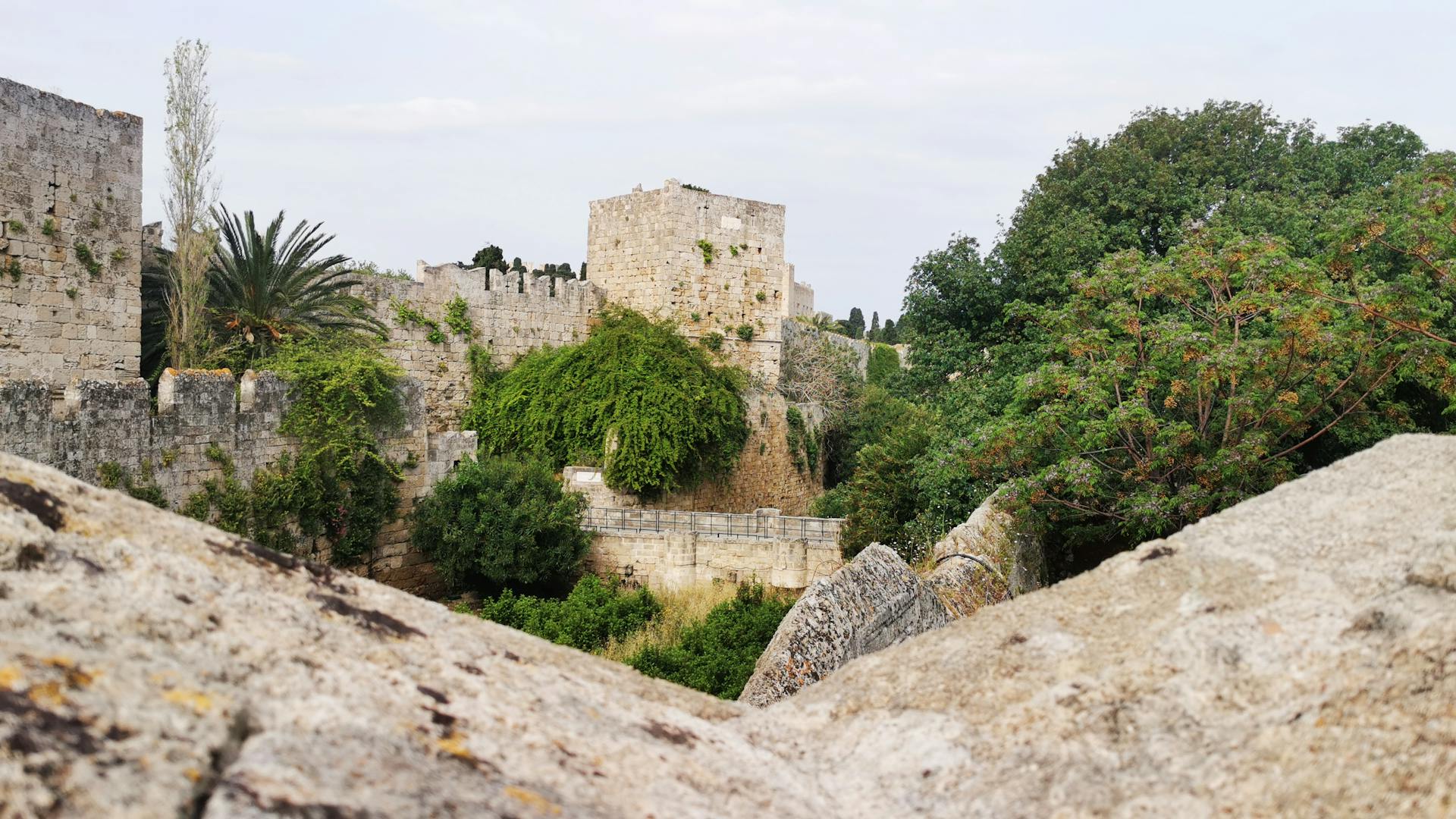 Explore the historic medieval castle walls covered in lush greenery in Rodos, Greece.