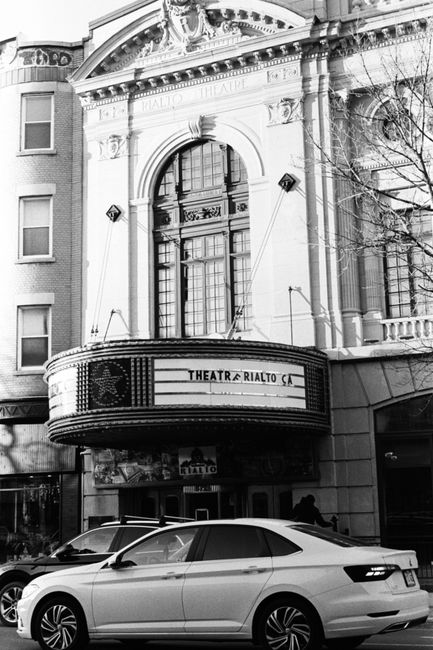 Dramatic black and white photo of a historical theater exterior in an urban setting.