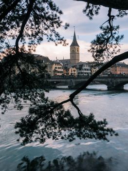 Picturesque scene of Zürich showcasing a historic bridge and church with tree framing.