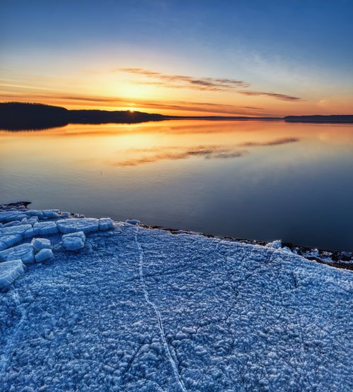 Free Serene winter sunrise with icy shoreline reflecting over calm Lake Pepin in Minnesota. Stock Photo